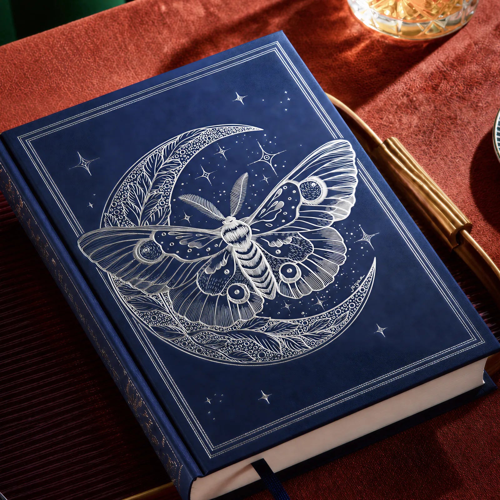 Libro con una polilla estampada en foil plateado sobre tapa azul
