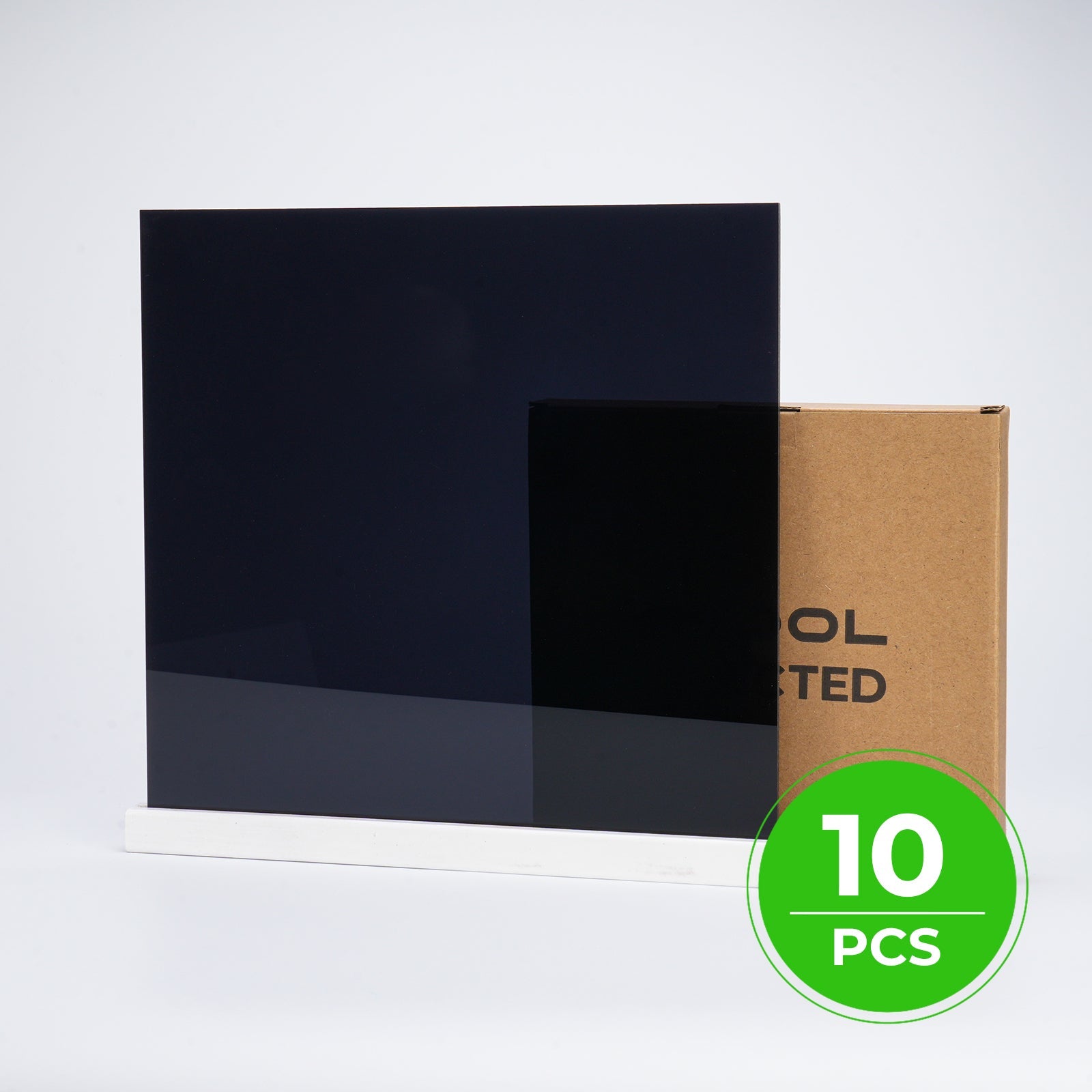 Dos láminas de acrílico negro brillante de 1 milímetro apoyadas sobre un soporte blanco, junto a la caja de cartón de xTool Selected y el chip que indica diez unidades
