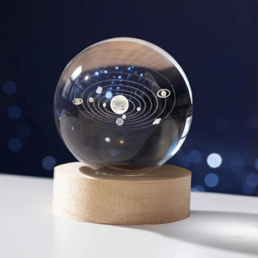 Bola de cristal K9 con el sistema solar grabado en su interior, iluminada sobre su base LED