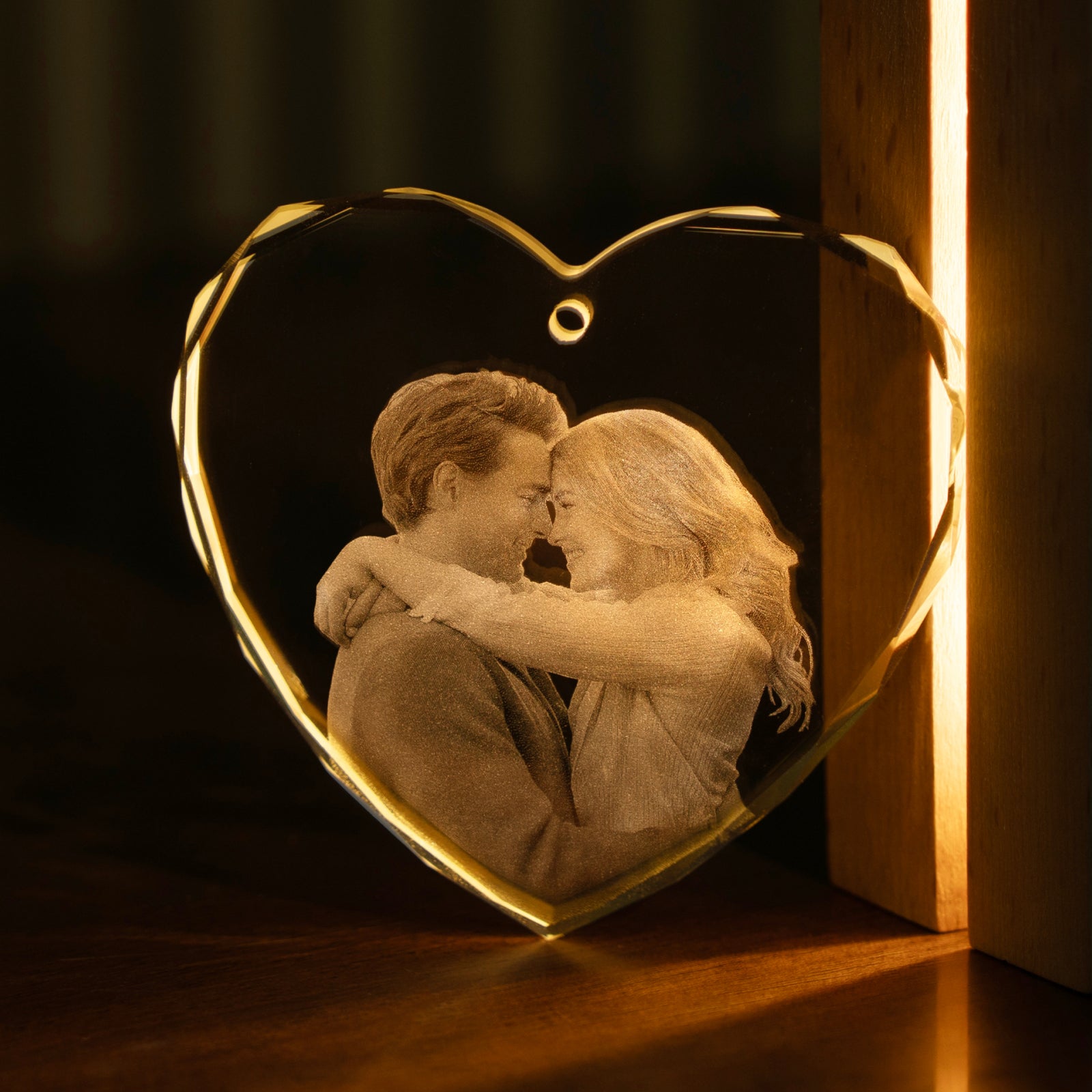 Corazon de cristal K5 facetado iluminado a contraluz, con una pareja abrazada grabada en su interior