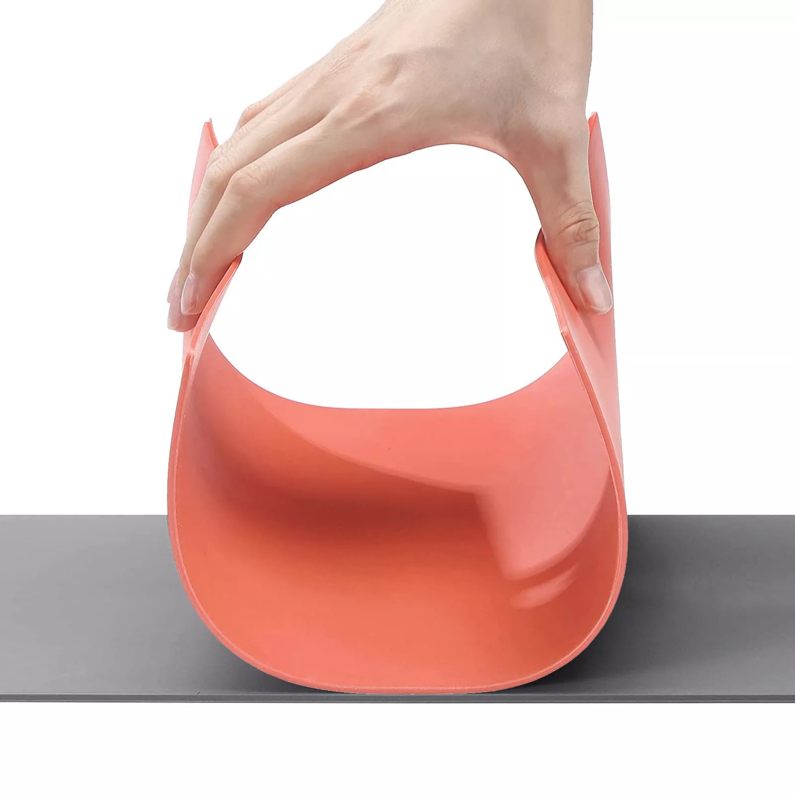 Una mano doblando la plancha de caucho roja sobre la gris, que demuestra que el material es flexible y no se quiebra