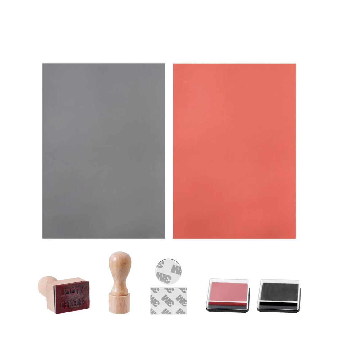 El set de sellos de caucho completo sobre fondo blanco: dos planchas de caucho, una gris y otra roja, dos mangos de madera —uno con el caucho ya montado y grabado—, dos adhesivos de doble cara 3M y dos tampones de tinta, uno rojo y otro negro